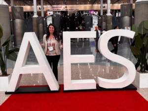 Jenifer smiling behind an AES sign