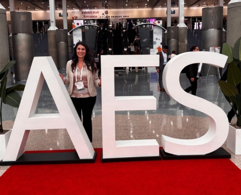 Jenifer smiling behind an AES sign