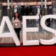 Jenifer smiling behind an AES sign