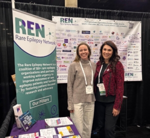 Michaelle Jinnettee and Jenifer Merriam smiling in front of Rare Epilepsies Network banners